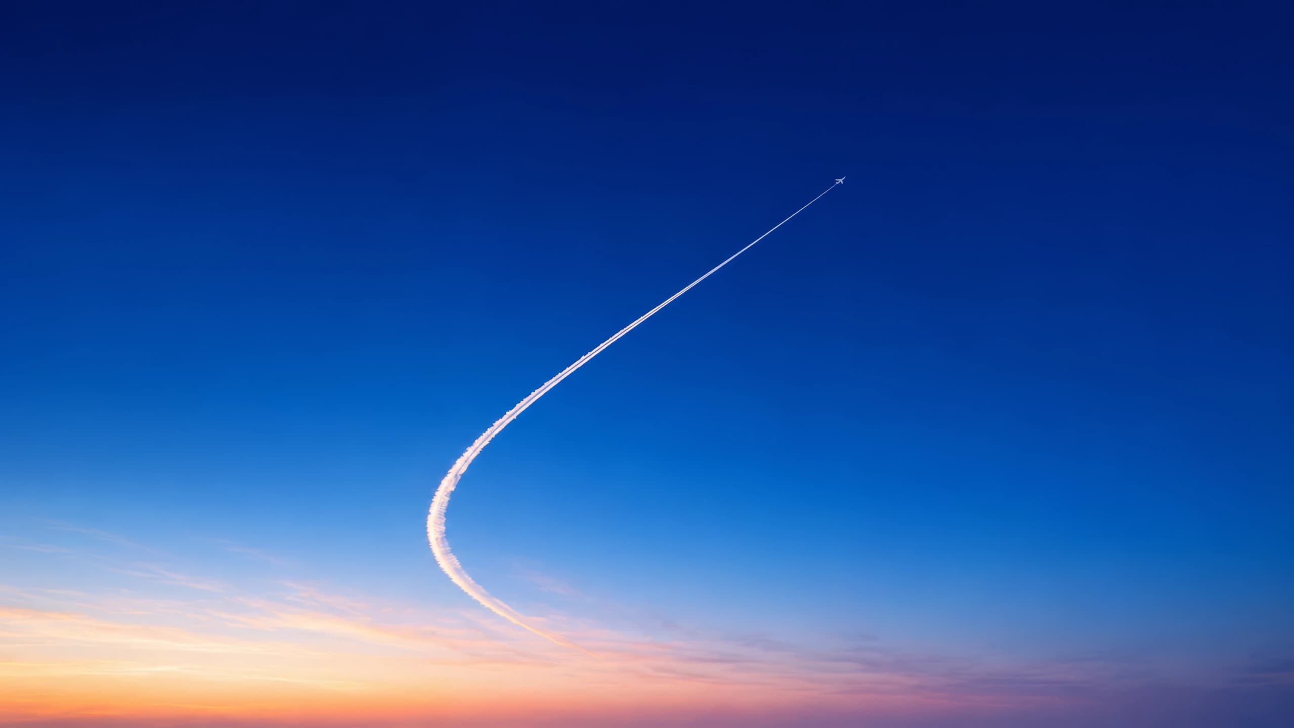 Airplane trail in a blue sunset sky
